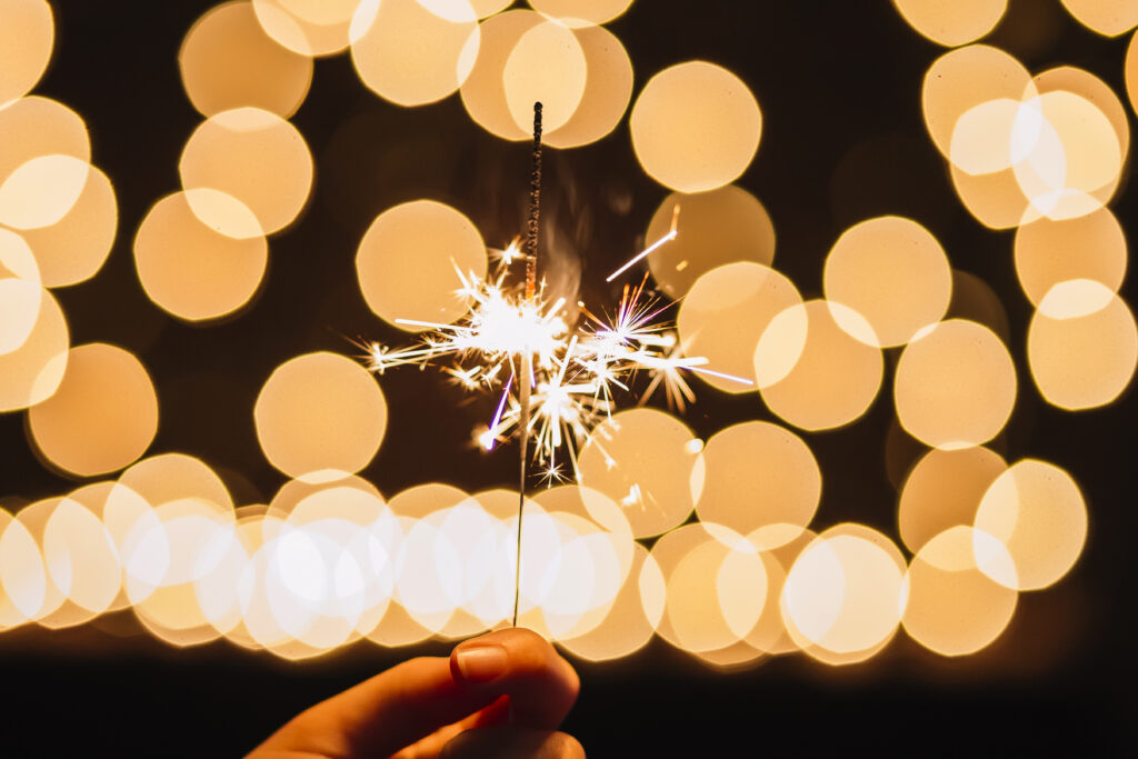 crop hand holding sparkler near lights Краснодарские известия