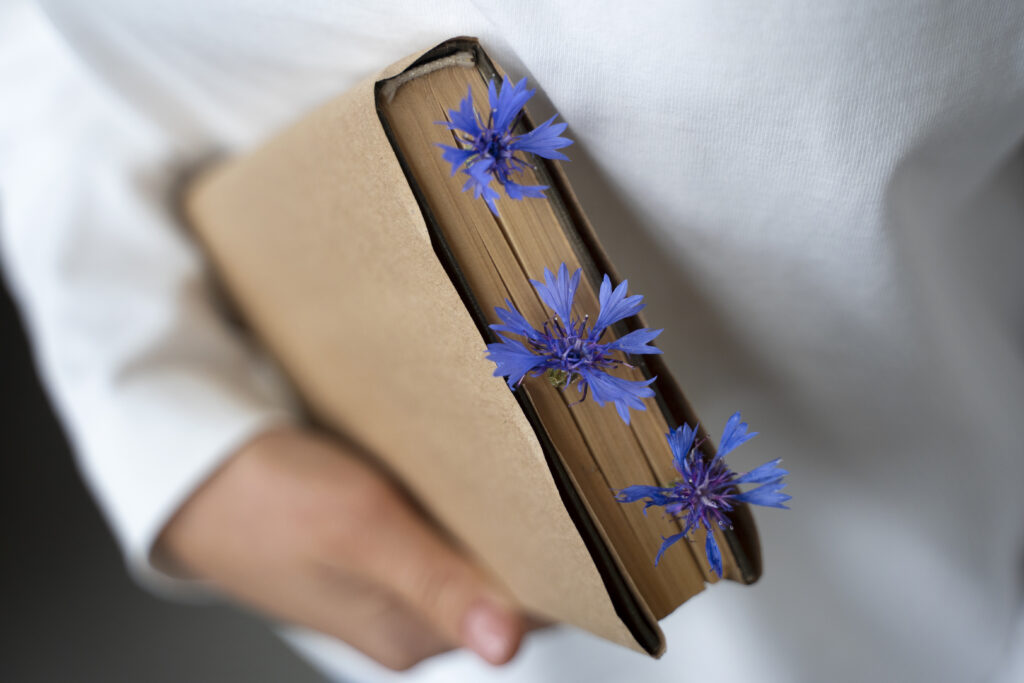 model holding book with flowers high angle Краснодарские известия